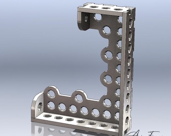 May include: An L-shaped metal bracket with a silver finish, featuring a series of circular cutouts along its vertical and horizontal segments. The structure includes integrated tabs with holes at the ends and the text Ariana France at the bottom.