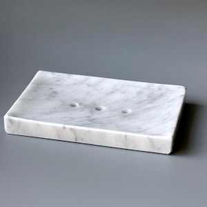 May include: White marble soap dish with three drainage holes.