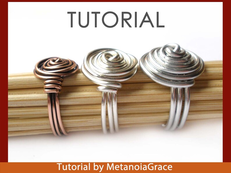 Pu&ograve; includere: Tre anelli di filo con un design a spirale. Gli anelli sono realizzati in filo di rame, argento e oro. Gli anelli sono esposti su una superficie di legno. Tutorial di MetanoiaGrace.