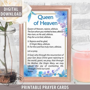 May include: Printable prayer card with a watercolor background featuring blue and purple flowers. The card features the text "Queen of Heaven" and a prayer to the Virgin Mary.