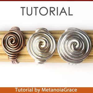 Pu&ograve; includere: Tre anelli di filo con un design a spirale. Gli anelli sono realizzati in filo di rame, argento e oro. Gli anelli sono esposti su una superficie di legno. Tutorial di MetanoiaGrace.