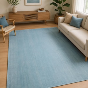 Könnte beinhalten: Ein großer rechteckiger Teppich in einfarbigem Hellblau mit einer glatten, gleichmäßigen Textur. Der Teppich verfügt über eine einfache, eingefasste Kante im gleichen hellblauen Farbton und bedeckt einen Großteil des hellen Holzbodens.