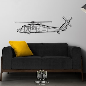 Puede incluir: Silueta negra de metal de un helicóptero colgada en una pared blanca sobre un sofá negro con un cojín amarillo. El sofá está delante de una lámpara de pie con una pantalla negra.