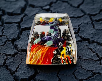 May include: A clear, rectangular keycap with a detailed, colorful scorpion design. The scorpion is purple with blue claws, set against a fiery red and yellow background. The keycap is a unique accessory for mechanical keyboards.