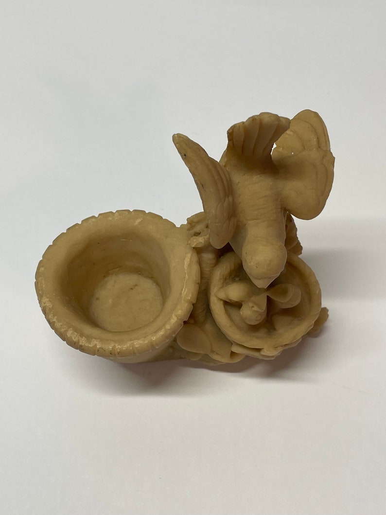 Peut inclure: Sculpture d&eacute;corative beige repr&eacute;sentant un oiseau aux ailes d&eacute;ploy&eacute;es au-dessus d'un petit r&eacute;cipient ouvert. La sculpture pr&eacute;sente un design sculpt&eacute; d&eacute;taill&eacute; et est faite d'un mat&eacute;riau solide.