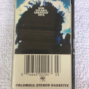 May include: A vintage cassette tape featuring Bob Dylan's Greatest Hits. The cover art showcases a silhouette against a blue and white background. The cassette has a barcode and the text "Columbia Stereo Cassette".