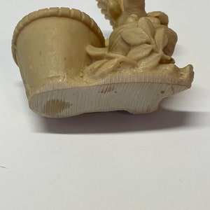 Peut inclure: Figurine beige repr&eacute;sentant un panier avec des fleurs et un oiseau. La figurine est faite d'un mat&eacute;riau de couleur claire et pr&eacute;sente des sculptures d&eacute;taill&eacute;es de feuilles et de p&eacute;tales. Le panier a un bord textur&eacute;.