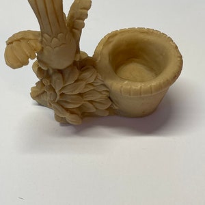Peut inclure: Figurine d'oiseau beige avec des ailes d&eacute;ploy&eacute;es et un petit panier. L'oiseau est perch&eacute; sur un lit de feuilles, et le panier est rond avec un bord textur&eacute;. La figurine est en mat&eacute;riau solide.