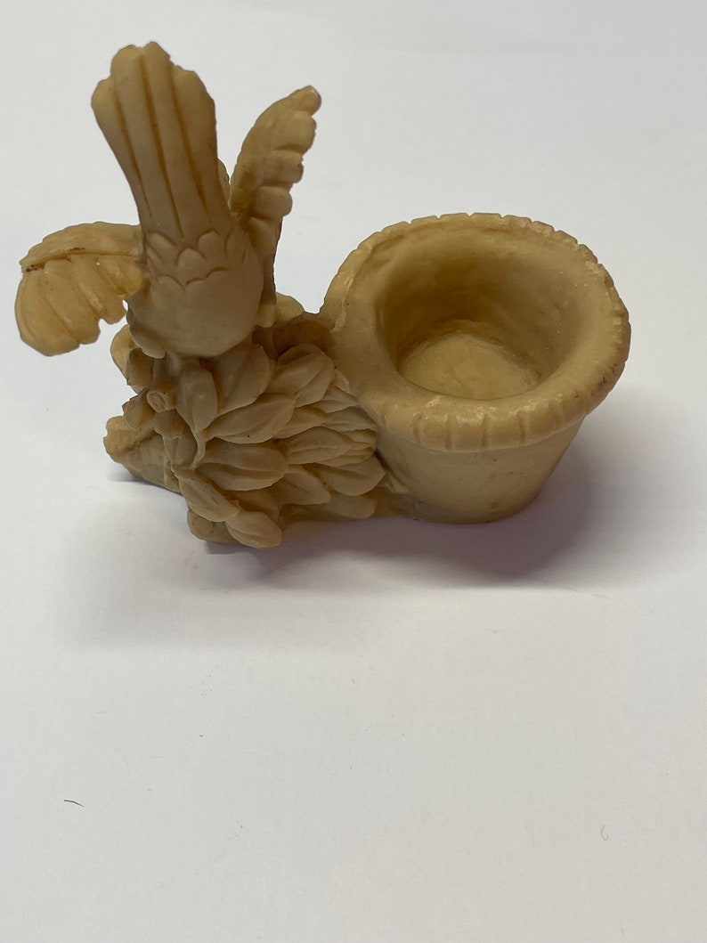 Peut inclure: Figurine d'oiseau beige avec des ailes d&eacute;ploy&eacute;es et un petit panier. L'oiseau est perch&eacute; sur un lit de feuilles, et le panier est rond avec un bord textur&eacute;. La figurine est en mat&eacute;riau solide.