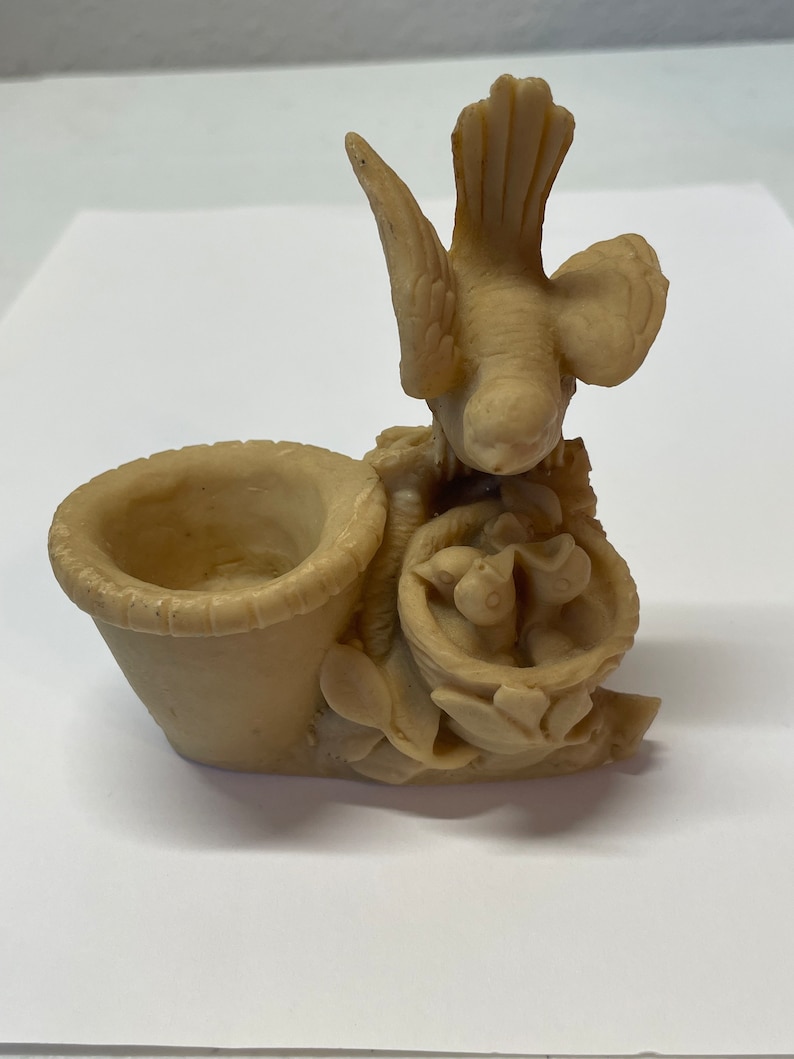 Peut inclure: Figurine beige repr&eacute;sentant un oiseau au-dessus d'un nid avec trois oisillons et un petit panier. Le panier est sur le c&ocirc;t&eacute; gauche de la figurine. La figurine est faite d'un mat&eacute;riau lisse.