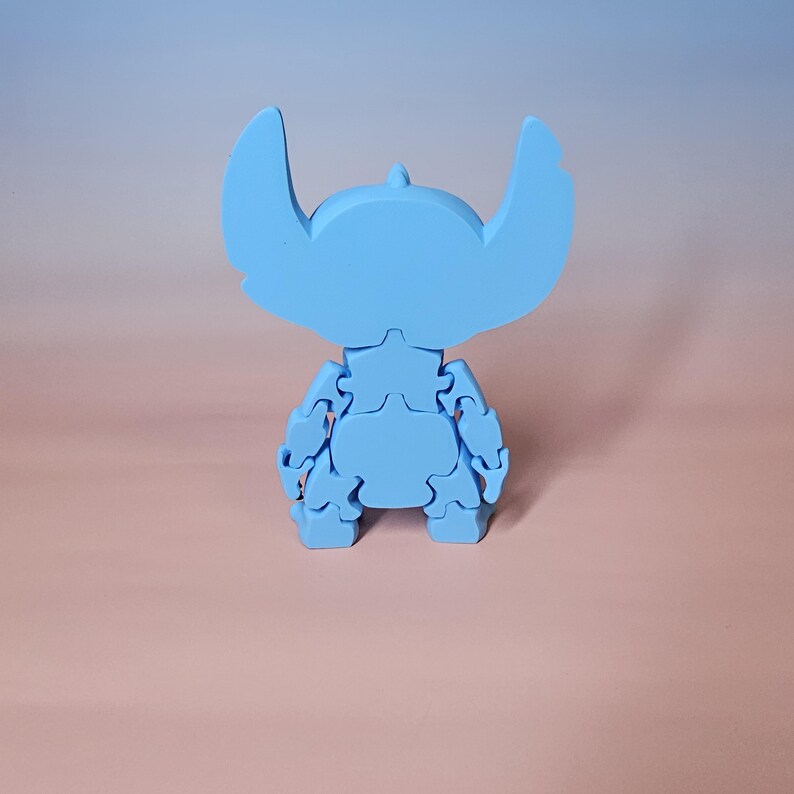 May include: A light blue puzzle depicting a cartoon character with large ears. The assembled puzzle stands on a surface with a pink and blue gradient background. The character's features are clearly visible.