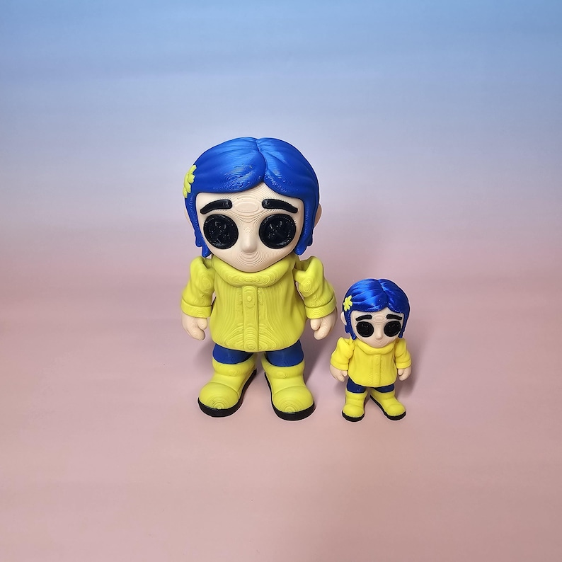 May include: Two figurines of a character with blue hair, yellow coat, and black eyes. The larger figure is approximately 5 inches tall, and the smaller one is about 3 inches tall. The background is a gradient of pink and blue.