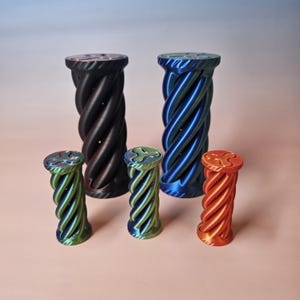 May include: A collection of decorative, twisted pillar-shaped objects in various sizes and colors. The colors include black, blue, green, and orange. The pillars have a spiral design and a flat top with a decorative pattern.
