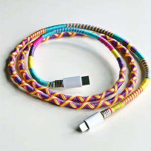 May include: A colorful braided phone charging cable with yellow, pink, and blue threads. The cable has a USB-C connector on one end and a Lightning connector on the other end.