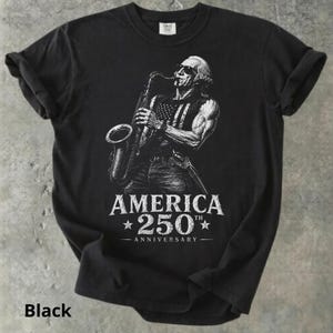 May include: Black t-shirt featuring a white graphic of a man playing a saxophone with an American flag design on his vest. The text "AMERICA 250th ANNIVERSARY" is printed below the image.