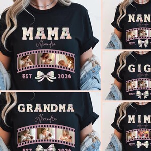 Op de afbeelding: Zwarte t-shirts met de woorden "MAMA", "GRANDMA", "NANA", "GIGI" en "MIMI". Elk shirt heeft een naam, een filmstrip met foto's, een strik en het jaar "2026" of "2024".