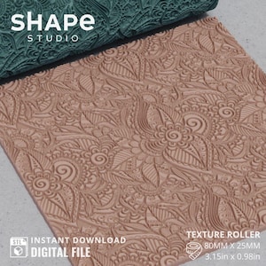 May include: A tan texture roller with a floral design, next to a teal roller with a similar pattern. The text "SHAPE STUDIO" is at the top left. The text "TEXTURE ROLLER" is at the bottom right. The roller is 3.15 inches by 0.98 inches.