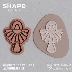 Könnte beinhalten: Zweiteiliges Set aus einem tonfarbenen Polymer-Ton-Ausstecher und einem passenden Abdruck. Der Ausstecher ist ein detailliertes, abstraktes Design mit fächerförmiger Gestaltung. Der Abdruck ist 60 mm x 44 mm groß.
