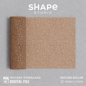 Puede incluir: Un rodillo de textura marrón con un patrón de superficie agrietada. El rodillo mide 80 mm x 25 mm y está etiquetado como "Rodillo de textura". La imagen también incluye el texto "SHAPE STUDIO" y "DESCARGA INSTANTÁNEA ARCHIVO DIGITAL".