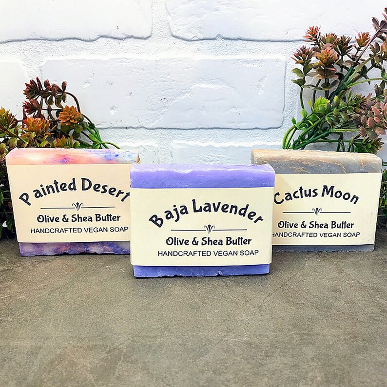 May include: Three bars of handmade vegan soap with labels that read "Painted Desert", "Baja Lavender", and "Cactus Moon". Each bar is made with olive and shea butter.