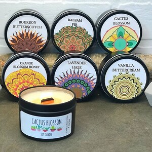 May include: Assortment of 10 scented soy candles in black tins with colorful mandala designs and white labels. The candle scents are: Bourbon Butterscotch, Balsam Fir, Cactus Blossom, Orange Blossom Honey, Lavender Haze, Vanilla Buttercream.