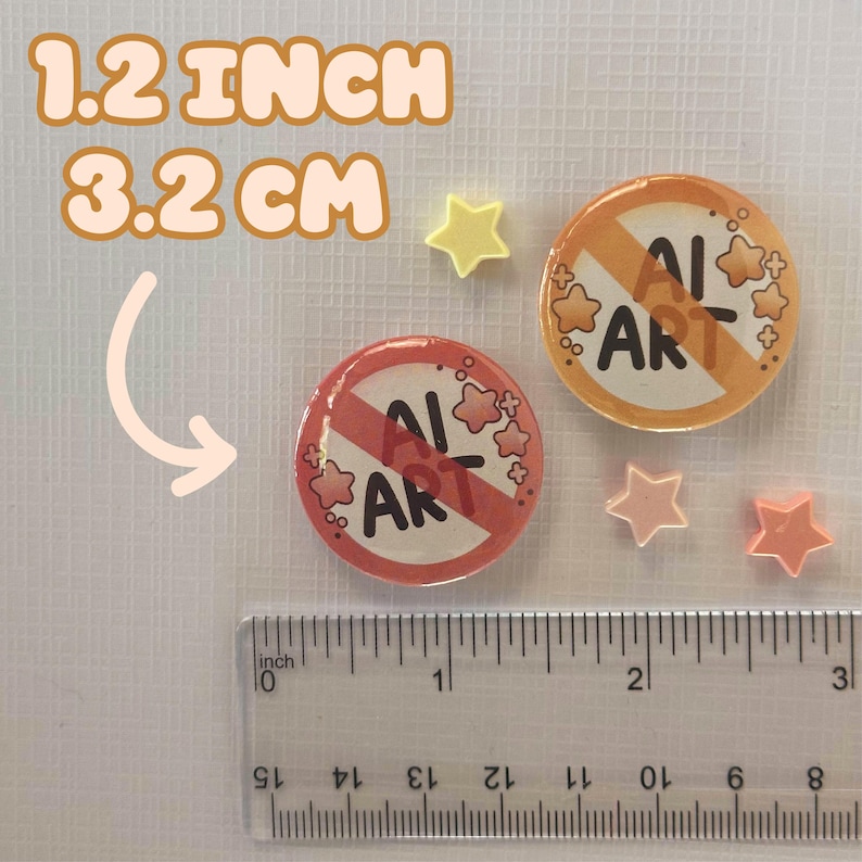 May include: Two round, 1.2-inch diameter buttons with a red and orange design that says "AI ART" with a no symbol. The image also includes three star-shaped embellishments and a ruler.