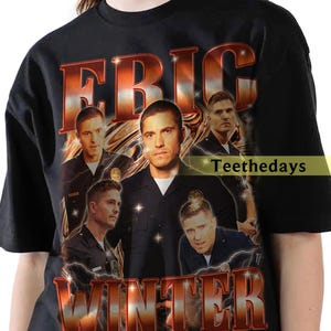 May include: Black t-shirt featuring a graphic of a man with the name "ERIC WINTER" in a bold, orange and red font. The design includes multiple images of the man in a police uniform, with lightning bolt effects.