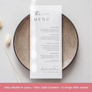 May include: A minimalist wedding menu card with the text "The Menu" in elegant script. The menu lists appetizers, starters, main course, and desserts. The bottom of the card includes the names "Amelia and James" and the date and location.
