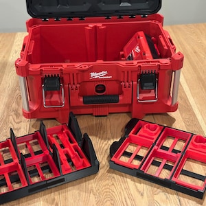 May include: Red Milwaukee Packout tool box with black latches and a black handle. Two black and red organizer trays are in front of the open box. The Milwaukee logo is visible on the front of the box.