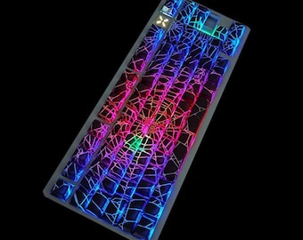 May include: A backlit mechanical keyboard with a unique design. The keys feature a web-like pattern with vibrant colors, including red, blue, and green. The keyboard has a compact layout and a dark background.