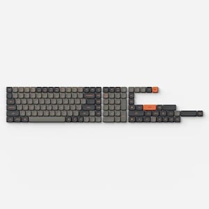 May include: A disassembled mechanical keyboard with gray keycaps and orange accent keys. The keys are arranged in sections, showcasing the individual components of the keyboard. The background is plain white.