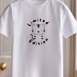 May include: White t-shirt with a cartoon tiger design in black and white, and the words "Limited Edition". The tiger has stripes and a friendly face. The t-shirt is displayed on a white hanger.