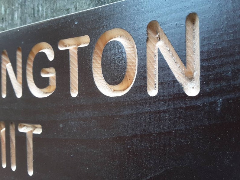 May include: A black wooden sign with the word "INGTON" carved into it in white.
