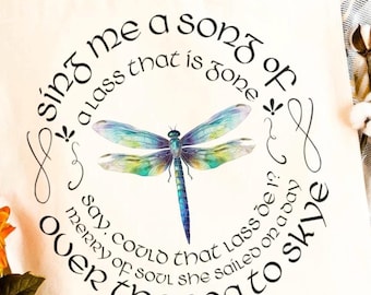 May include: Cream-colored tote bag featuring a watercolor dragonfly with blue, green, and yellow wings. The bag has a circular text design in black script that reads "Sing me a song of a lass that is gone...over the sea to Skye."