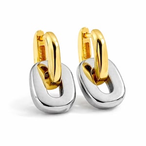May include: A pair of gold and silver-toned hoop earrings. The top portion of the earrings is gold, while the lower, chain-link-shaped portion is silver. The earrings are displayed against a white background.