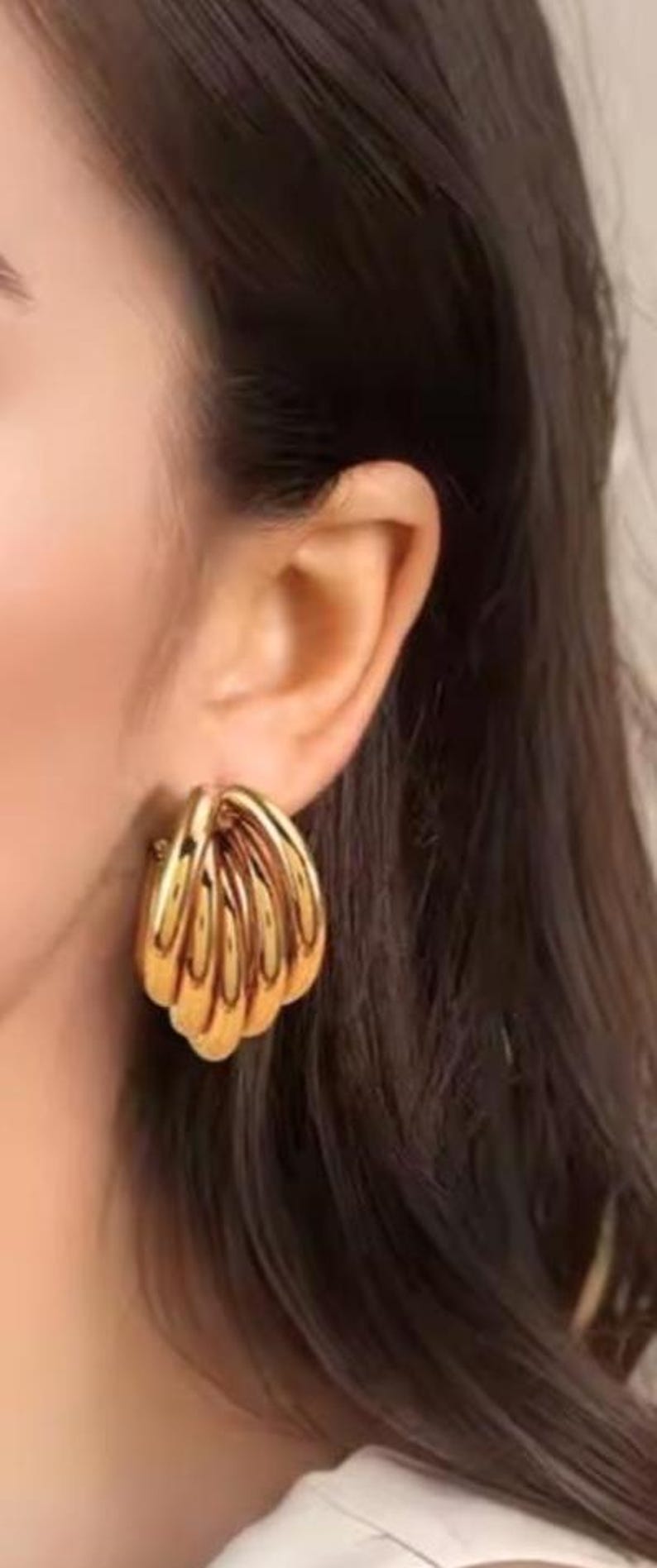 Puede incluir: Pendientes dorados con dise&ntilde;o de capas, con un dise&ntilde;o en forma de concha. Los pendientes son de estilo clip y tienen una superficie pulida y reflectante. La joyer&iacute;a es un accesorio audaz.