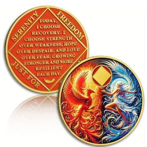 May include: Two gold-colored recovery coins. One coin features the words "Serenity" and "Freedom" with the text "Today, I choose recovery." The other coin depicts a phoenix and a woman with wings. The coins have a gold border.
