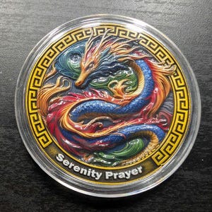 May include: A colorful coin featuring a detailed dragon design. The dragon is depicted in shades of blue, red, orange, and green, with intricate detailing. The coin has a gold border with a repeating pattern and the words "Serenity Prayer".