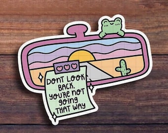 May include: A vibrant sticker depicting a car's rearview mirror with a sunset scene, a cactus, and a frog. The sticker includes the text: "Don't look back. You're not going that way."