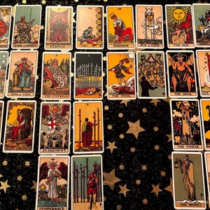 May include: A tarot card spread with 22 cards laid out on a black background with white stars. The cards include The Star, The Sun, The Devil, The Tower, The Empress, The Fool, The Hermit, The Hierophant, Judgement, Temperance, Strength, Justice, Wheel of Fortune, Queen of Swords, King of Cups, Ace of Wands, Ace of Cups, Ace of Swords, Knight of Pentacles, Queen of Pentacles, and Eight of Swords.