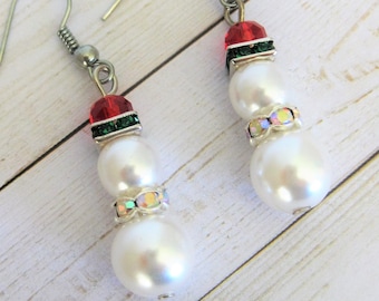 May include: A pair of silver snowman earrings with white pearl beads, red and green accents, and clear rhinestones.