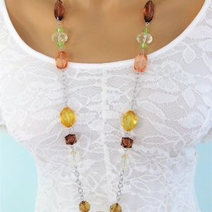 May include: A long silver chain necklace with faceted glass beads in shades of orange, brown, and green.