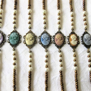 May include: Seven necklaces with brown and white beads and cameo pendants. The cameos are in shades of blue, green, pink, and white.