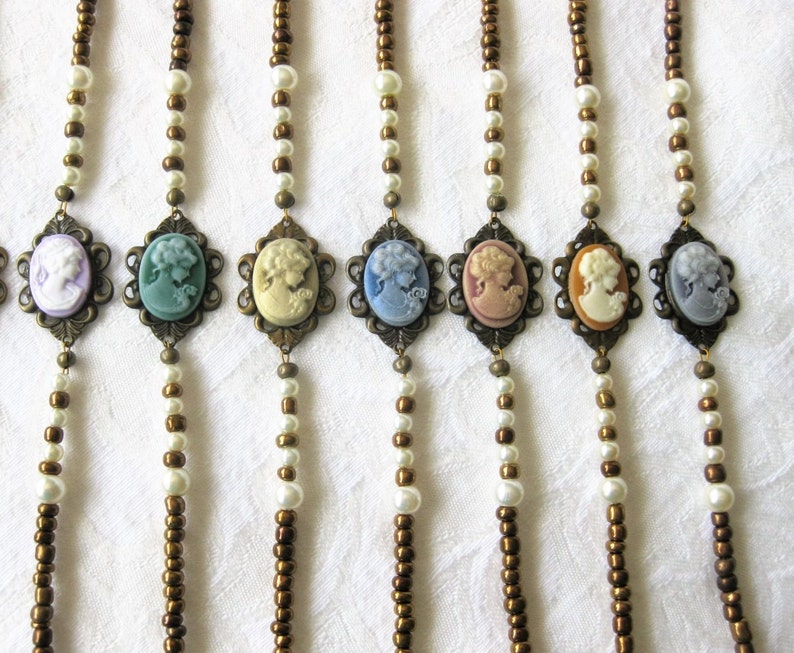 May include: Seven necklaces with brown and white beads and cameo pendants. The cameos are in shades of blue, green, pink, and white.