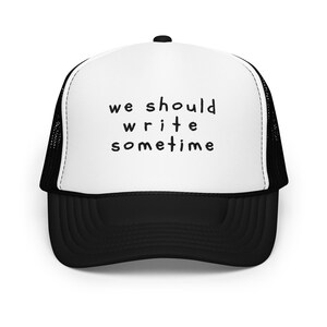 May include: A black and white trucker hat with a white front panel and a black mesh back. The front panel has the text "we should write sometime" in black.