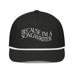May include: Black baseball cap with a white rope trim and white embroidered text that reads "Because I'm a Songwriter".