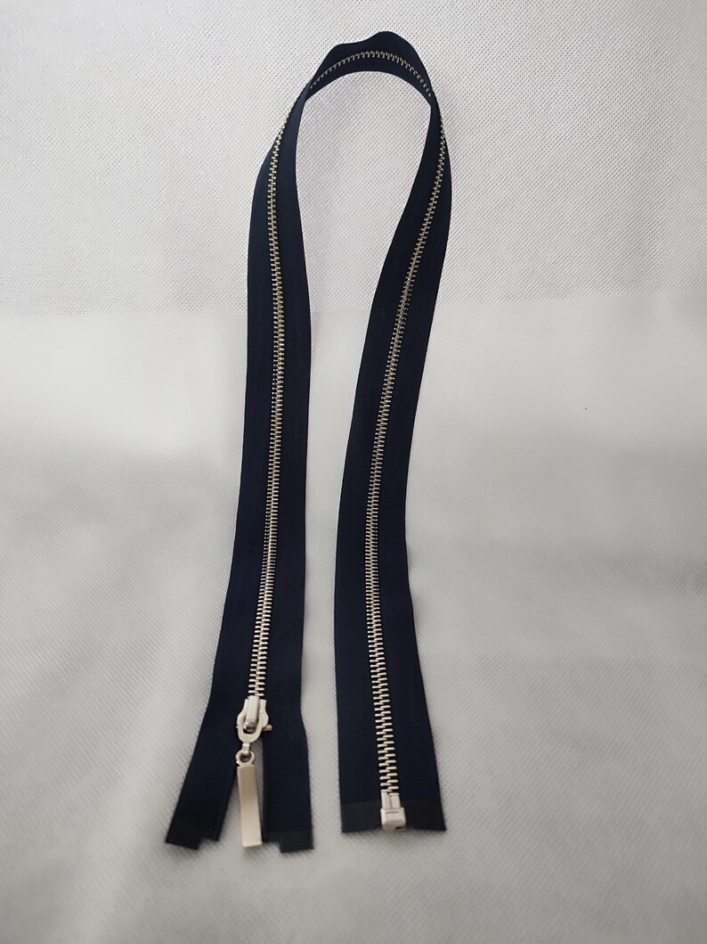 May include: Two navy blue zippers with silver metal teeth and pulls. The zippers are displayed against a white background. The zipper teeth are interlocked, and the pulls are rectangular.