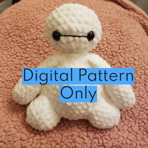 May include: White crocheted amigurumi toy resembling Baymax from the Disney movie Big Hero 6. The toy has black eyes and a black mouth. The text "Digital Pattern Only" is superimposed on the image.