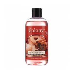 May include: A clear glass bottle with a black cap filled with a pink liquid. The bottle has a red label with the text "Colony" and "Cinnamon Spice Reed Diffuser Refill" in white. The label also includes a picture of cinnamon sticks and a gingerbread cookie. The bottle contains 250 ml / 8.4 fl oz.