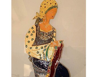 Può includere: Decorazione murale raffigurante una donna in abiti tradizionali. La figura indossa un foulard giallo e un abito fantasia con dettagli neri e dorati. L'opera d'arte presenta dettagli intricati e una posa seduta.
